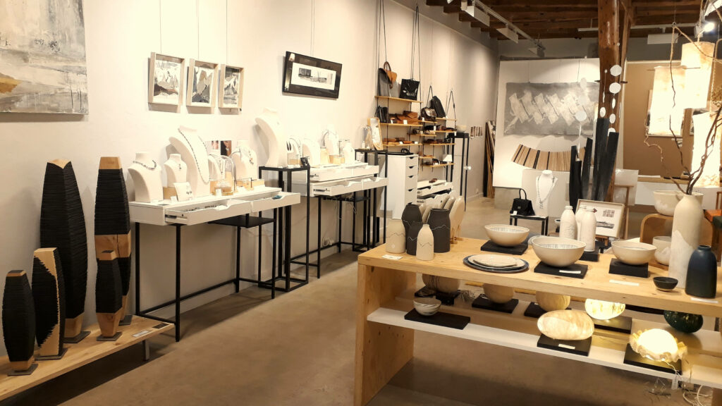 Vue d'ensemble de la galerie CARACTÈRES à Chambéry : céramiques, sculptures sur bois, bijoux, peintures, maroquinerie.